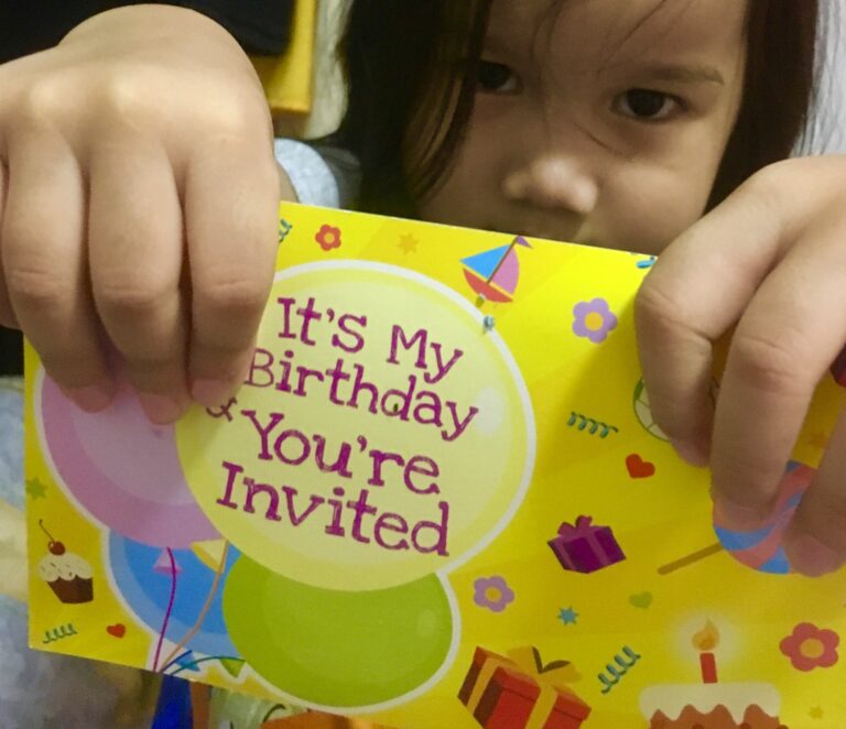 Serious kid flashing a birthday invitation card